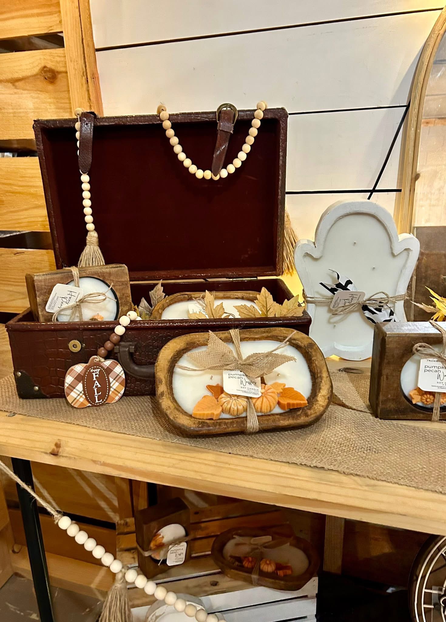 Wooden dough bowl candles with fall decorations displayed in a vintage suitcase.